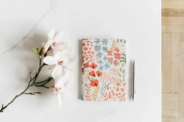 bookkeeping preperation Floral notebook and pen on a marble table, symbolizing organization and creativity for bookkeeping tasks.