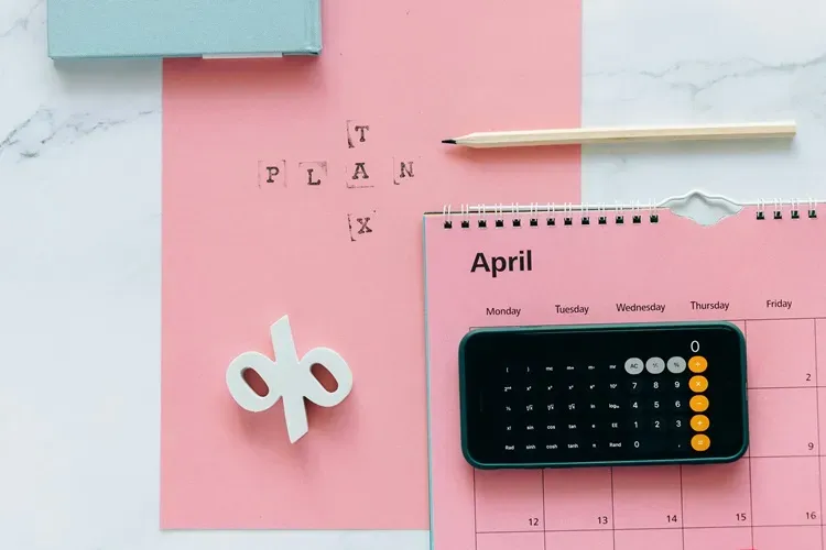 Calculator on smartphone, pink calendar for April, tax planning text, and stationery, symbolizing VAT compliance and bookkeeping support for small businesses.