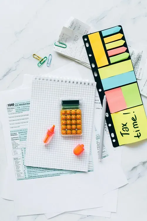 tax preparation - tax time Calculator, highlighters, notepad, and tax documents arranged on a desk, symbolizing tax preparation and bookkeeping services for small businesses.